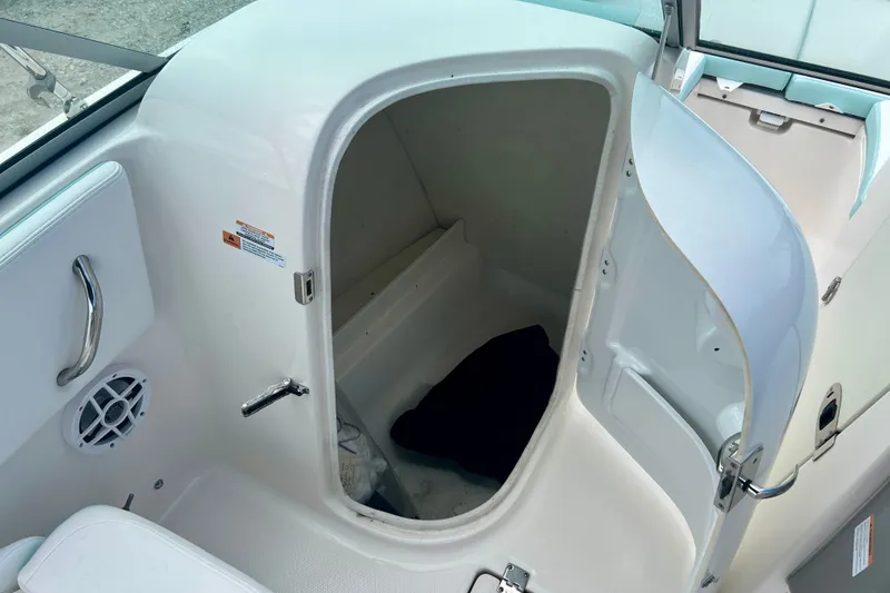 Slide: The Image of 2024 Robalo R207 Dual Console boat storage compartment with open door and interior view. - 15