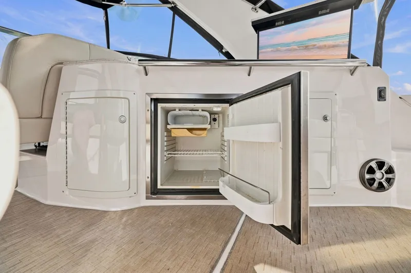Slide: The Image of Open mini fridge on 2018 Regal 33 XO boat, showcasing interior storage space. - 47