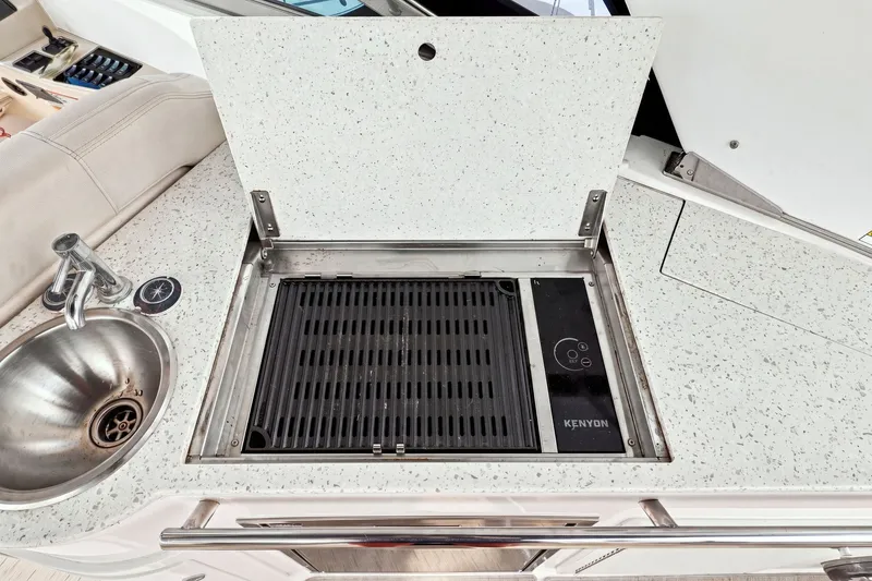 Slide: The Image of 2018 Regal 33 XO yacht kitchenette with Kenyon grill and stainless steel sink. - 59