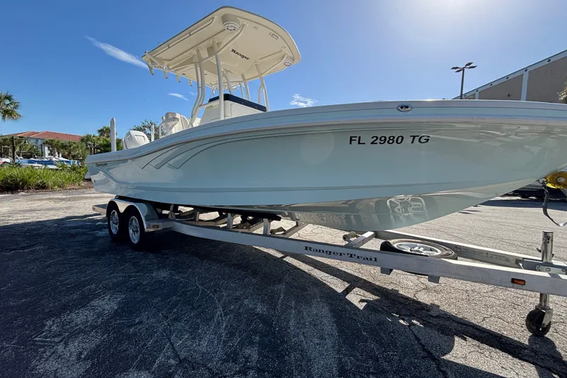 Slide: The Image of 2022 Ranger 2660 Bay boat on trailer, parked outdoors under clear sky. - 3