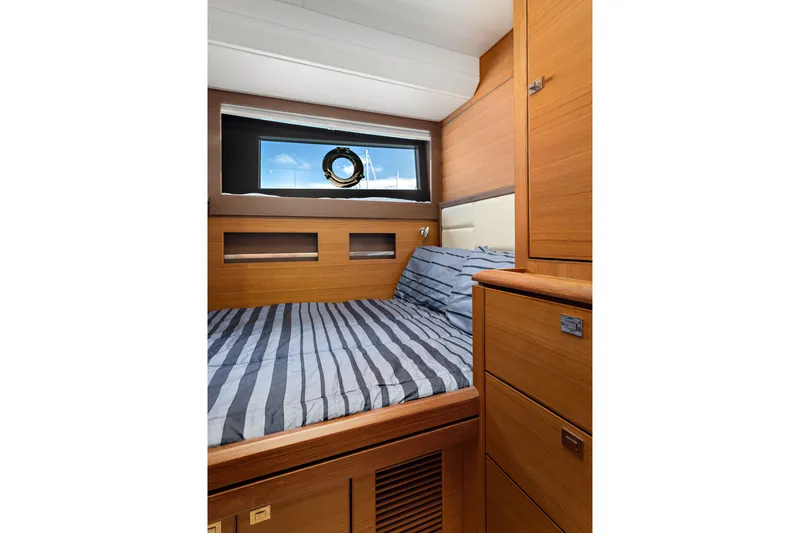 Slide: The Image of 2024 North Pacific 450 Pilothouse cabin with striped bedding and wooden interior. - 17