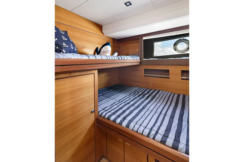 Slide: The Image of 2024 North Pacific 450 Pilothouse cabin with wooden interior and striped bedding. - 18