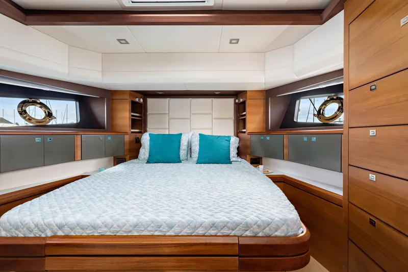 Slide: The Image of Luxurious 2024 North Pacific 450 Pilothouse bedroom with elegant wood finishes and teal accents. - 13