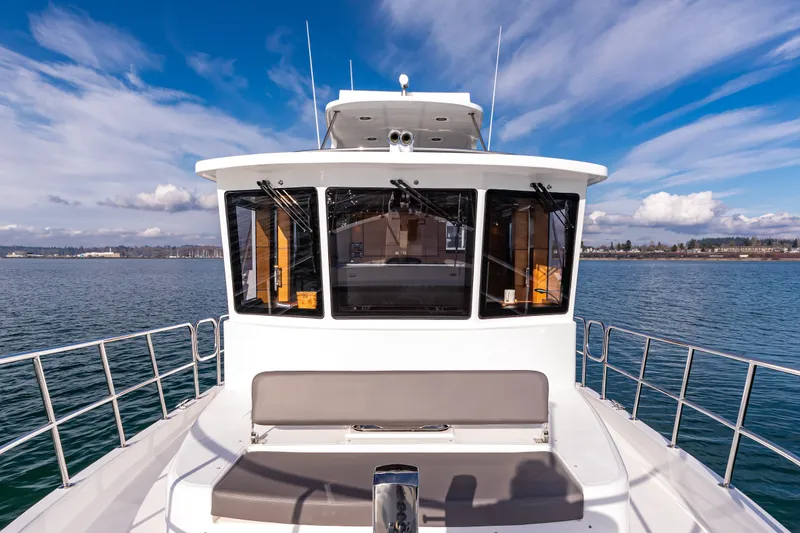 Slide: The Image of 2024 North Pacific 450 Pilothouse yacht on calm water under blue sky. - 24