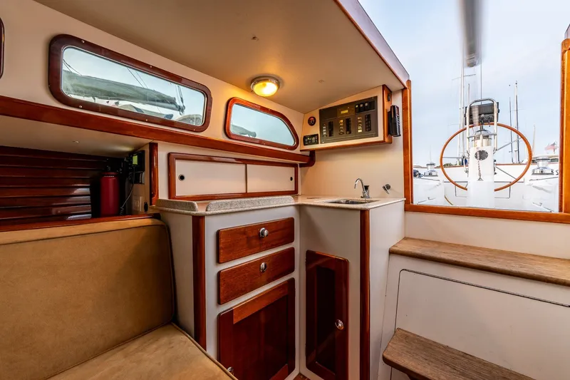 Slide: The Image of Interior of a 2005 Morris M36 sailboat featuring a compact galley with wooden cabinetry. - 25