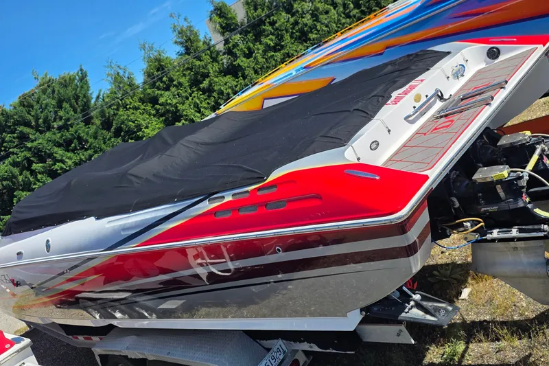 Slide: The Image of 2007 Donzi 38 ZR speedboat with vibrant red and white design, covered and parked outdoors. - 1