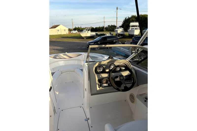 Slide: The Image of 2006 Yamaha Boats AR230 cockpit with steering wheel and dashboard, parked outdoors. - 13
