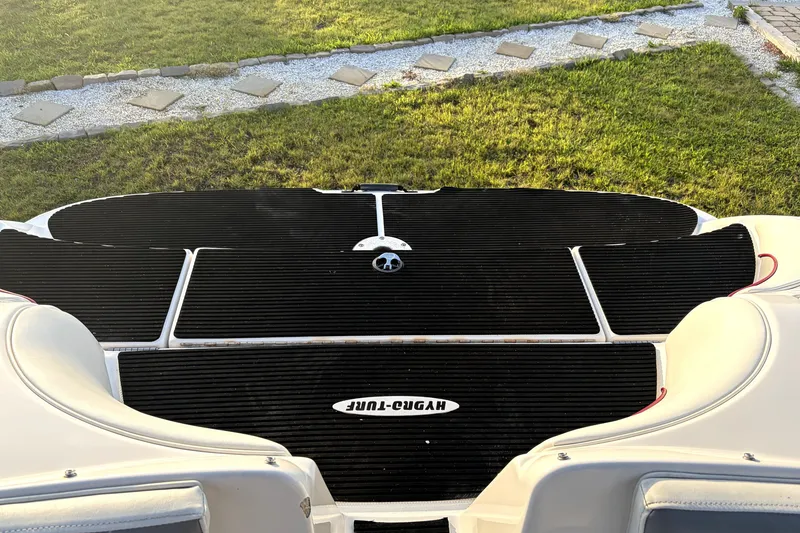 Slide: The Image of 2006 Yamaha Boats AR230 swim platform with black matting, surrounded by grass and stone path. - 3