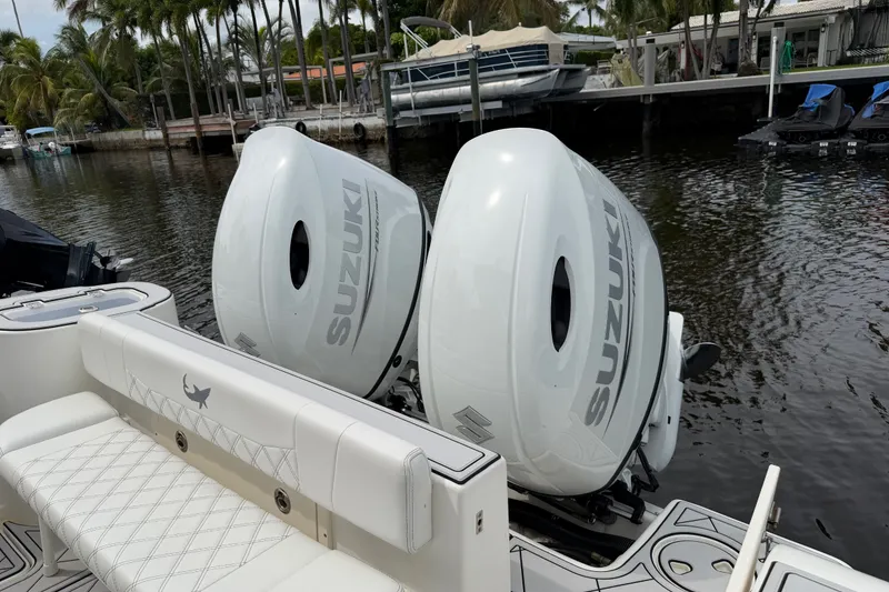 Slide: The Image of 2019 Mako 284 Center Console with twin Suzuki outboard motors docked by palm trees. - 36