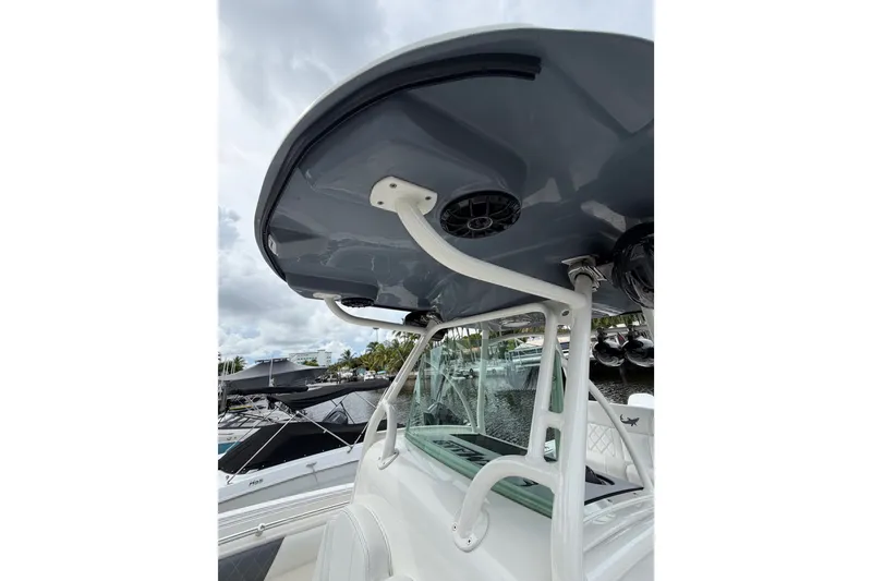 Slide: The Image of 2019 Mako 284 Center Console boat with T-top and speakers, docked at marina. - 20