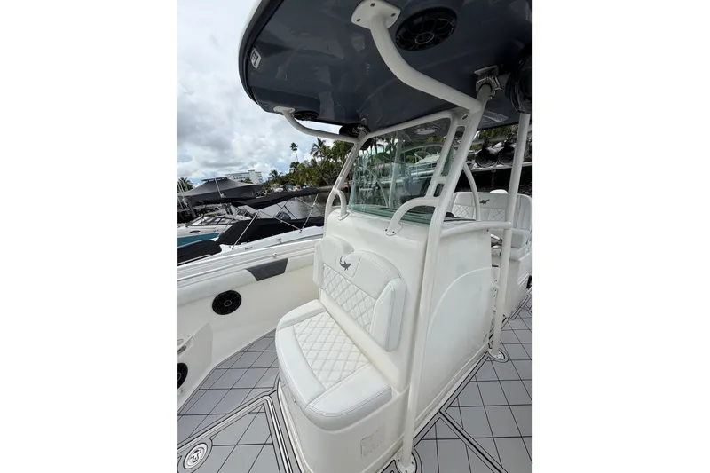 Slide: The Image of 2019 Mako 284 Center Console boat interior with white seating and overhead speakers. - 21