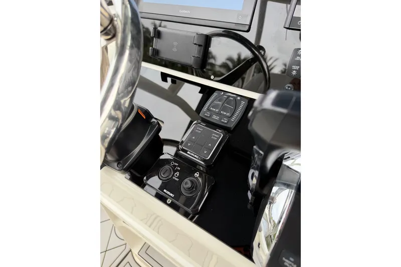 Slide: The Image of 2019 Mako 284 Center Console boat dashboard with Suzuki controls and Garmin display. - 14