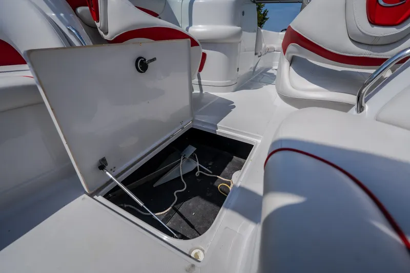 Slide: The Image of 2009 Crownline 260 LS boat interior with open storage compartment and red-accented seating. - 34