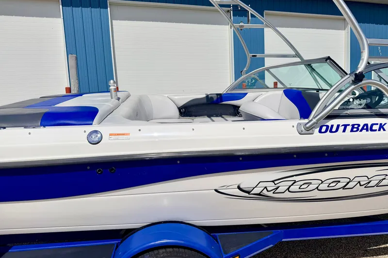 Slide: The Image of 2007 Moomba Outback V boat with blue and white design, parked near a blue building. - 12