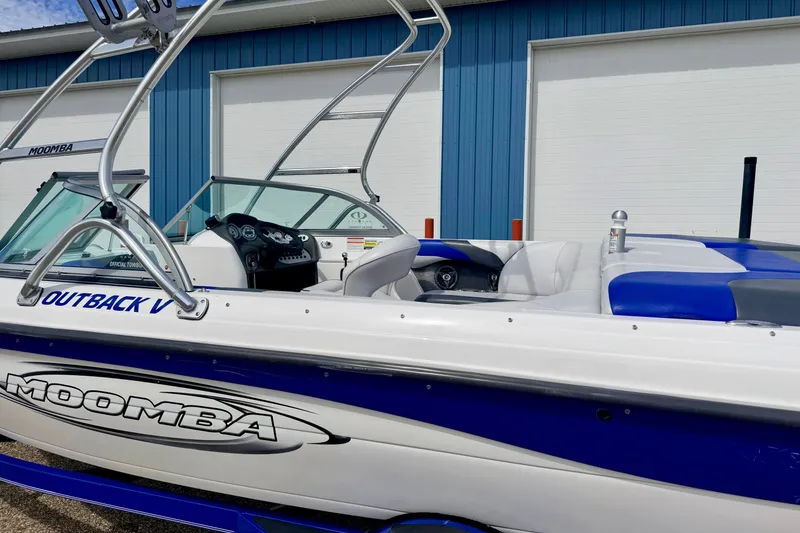 Slide: The Image of 2007 Moomba Outback V boat with blue and white design, parked near a blue building. - 10