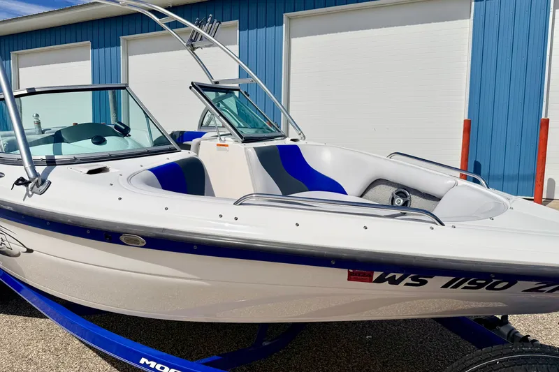 Slide: The Image of 2007 Moomba Outback V boat with blue accents, parked near a blue building. - 11