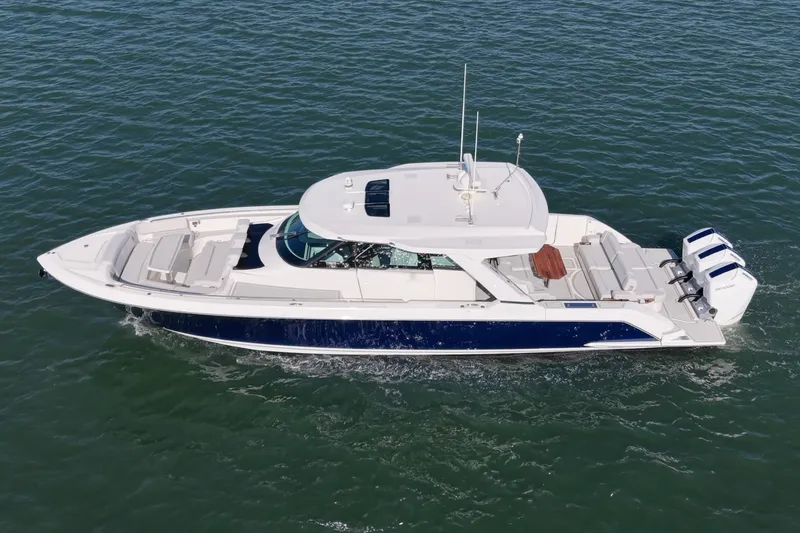 Slide: The Image of The 2023 Tiara Yachts 48 LS is a sleek boat with a blue hull and three outboard engines. - 4