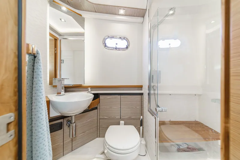 Slide: The Image of The image shows a modern yacht bathroom with a sink, toilet, and shower. - 49