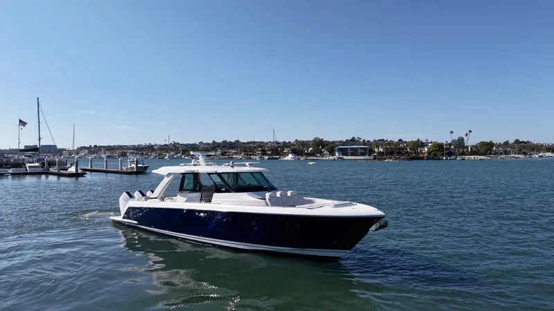 Slide: The Image of The 2023 Tiara Yachts 48 LS cruises on calm waters with a cityscape in the background. - 6