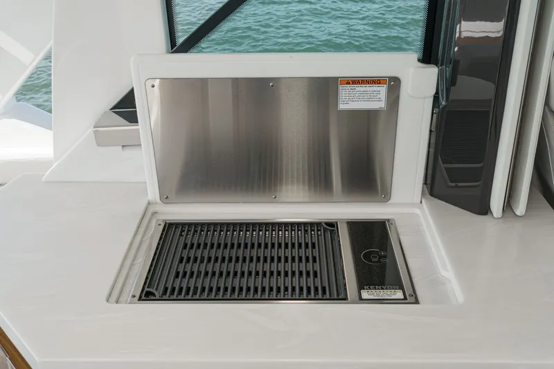 Slide: The Image of A built-in grill on a yacht with a stainless steel cover and warning label. - 27