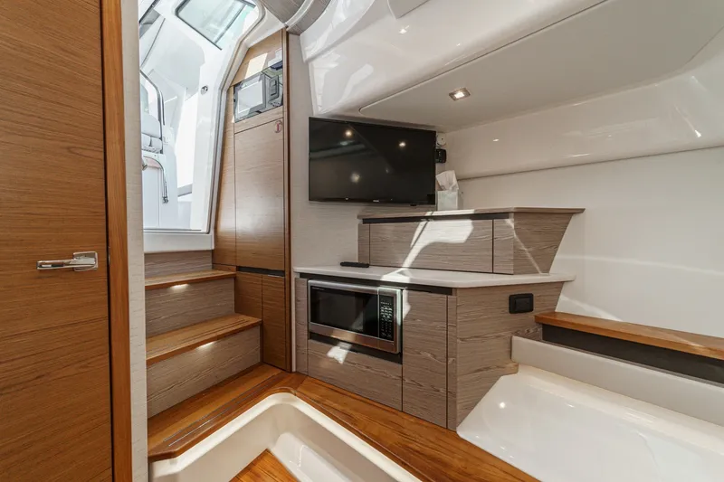 Slide: The Image of Interior of a modern yacht with wood paneling, stairs, a TV, and a microwave. - 47