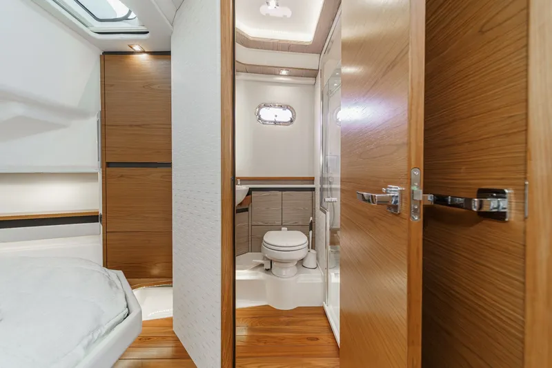 Slide: The Image of Interior of a 2023 Tiara Yachts 48 LS featuring a modern bathroom and wooden doors. - 48