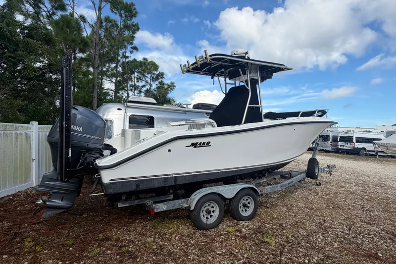 Slide: The Image of 2000 Mako 232 Center Console boat on trailer, parked outdoors with Yamaha engine. - 2