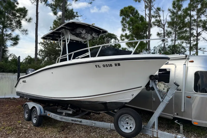 The Image of 2000 Mako 232 Center Console boat on trailer, parked outdoors near trees. - 0