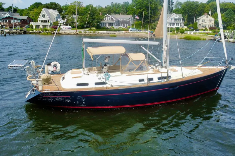 Slide: The Image of Sailboat Moody 42 (2000) on water near coastal homes, featuring sleek design and spacious deck. - 44