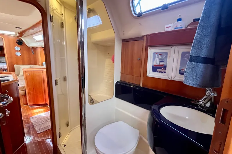 Slide: The Image of Interior of a 2000 Moody 42 yacht featuring a compact bathroom with shower and sink. - 19