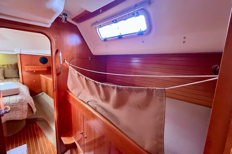 Slide: The Image of Interior of a 2000 Moody 42 sailboat, featuring cozy wooden cabin and sleeping area. - 14