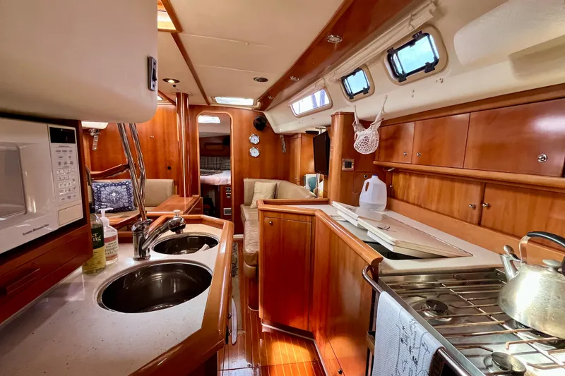 Slide: The Image of Interior of a 2000 Moody 42 yacht, featuring a cozy kitchen and dining area. - 23