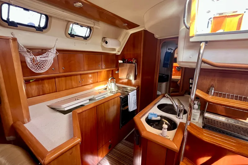 Slide: The Image of Cozy kitchen area in a 2000 Moody 42 yacht, featuring wooden cabinetry and dual sinks. - 24