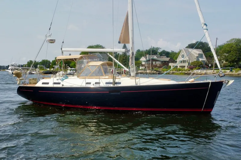 Slide: The Image of Sailboat Moody 42, 2000 model, cruising near coastal homes on a sunny day. - 1