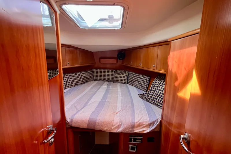 Slide: The Image of Cozy cabin interior of 2000 Moody 42 sailboat with striped bedding and wooden finish. - 8