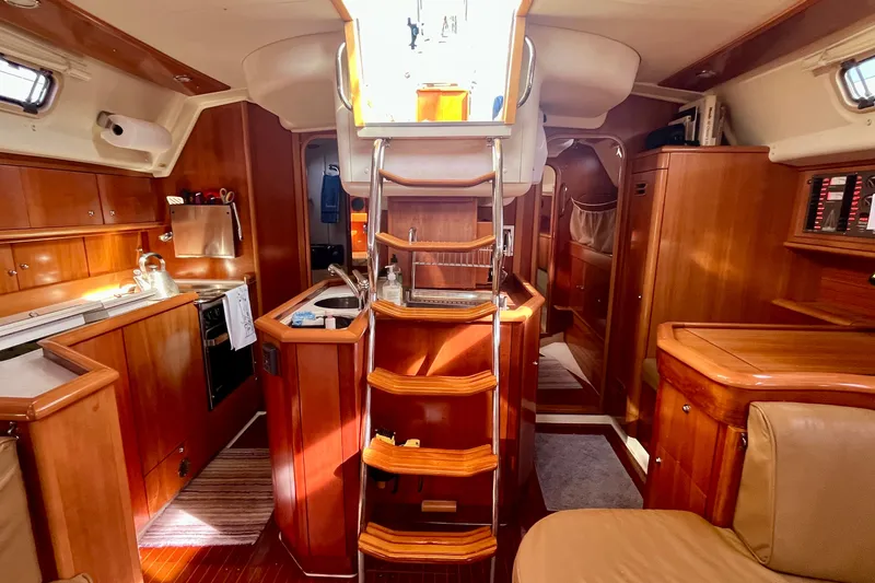 Slide: The Image of Interior of a 2000 Moody 42 yacht, featuring wooden cabinetry and a compact kitchen. - 27