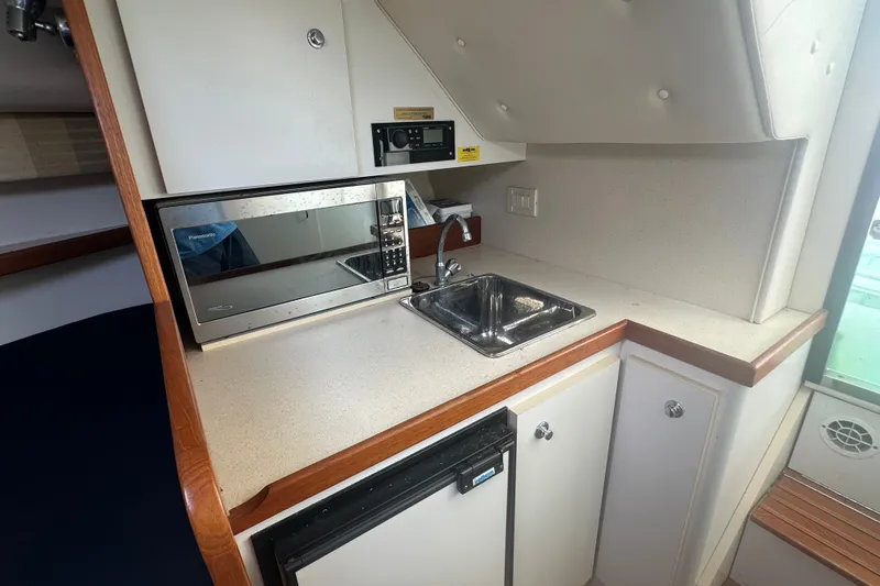 Slide: The Image of 2005 Tiara Yachts 2900 Coronet kitchenette with microwave, sink, and compact fridge. - 16