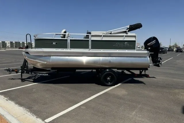 The Image of 2027 Sun Tracker Bass Buggy 16 XL Select pontoon boat on trailer in parking lot. - 0