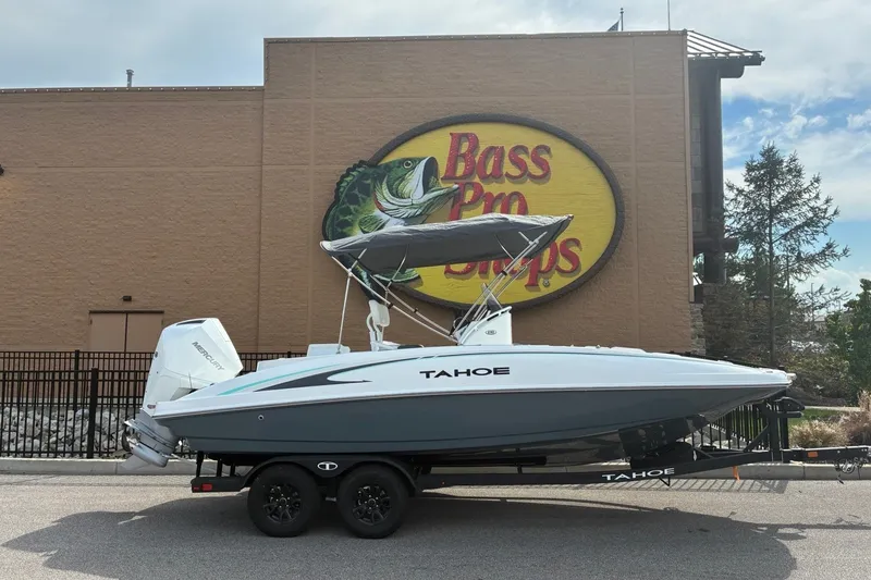 The Image of A white 2027 Tahoe 2150 CC boat on a trailer in front of a Bass Pro Shops building. - 0