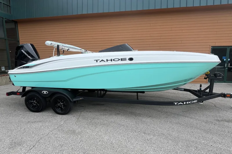 Slide: The Image of 2027 Tahoe T21 boat with turquoise hull on a trailer, parked outdoors. - 1