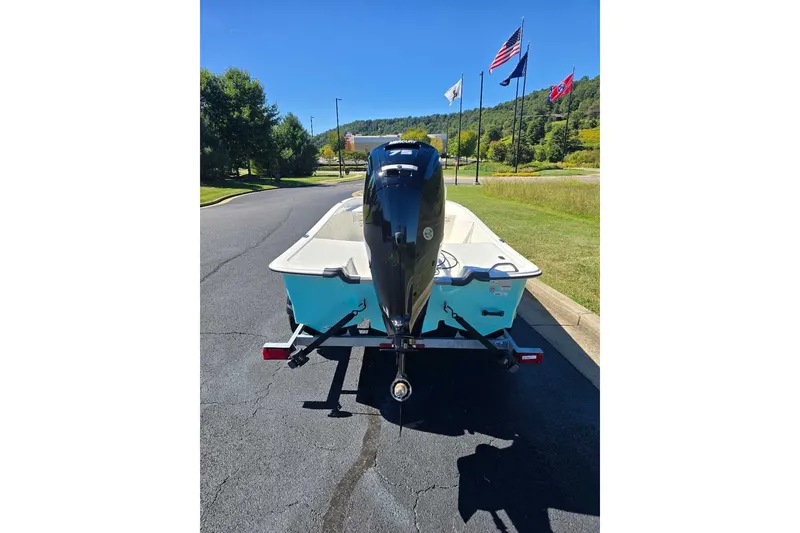 Slide: The Image of 2027 Mako Pro Skiff 17 CC boat on trailer, flags in background, sunny day. - 4