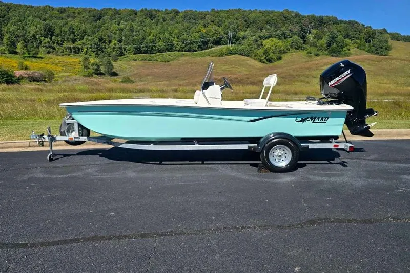 Slide: The Image of 2027 Mako Pro Skiff 17 CC boat on trailer, parked outdoors with scenic background. - 2