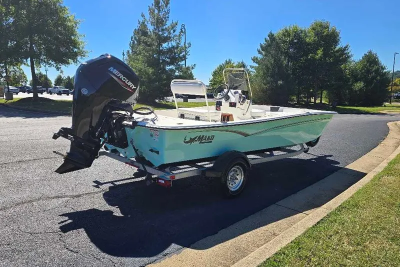The Image of 2027 Mako Pro Skiff 17 CC boat on trailer, parked outdoors, with Mercury outboard motor. - 0