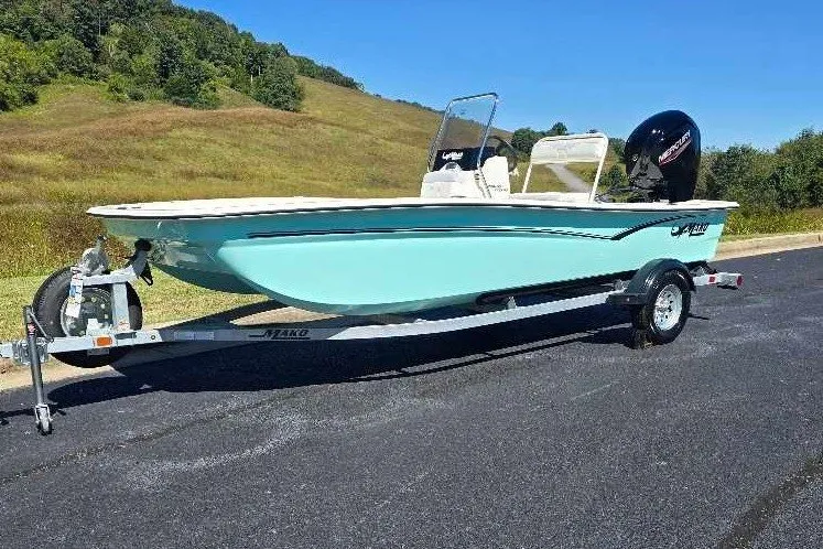 Slide: The Image of 2027 Mako Pro Skiff 17 CC boat on trailer, parked on asphalt road. - 1