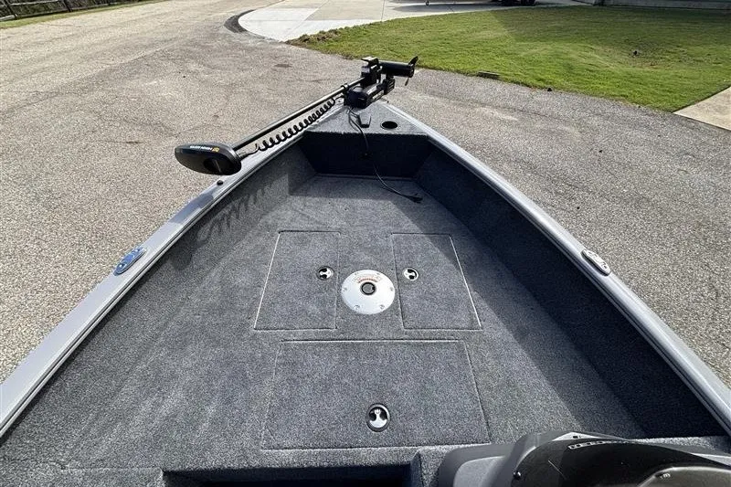 Slide: The Image of 2027 Tracker Super Guide V-16 SC boat deck with trolling motor, parked on pavement. - 15