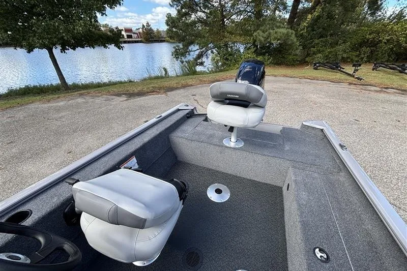 Slide: The Image of 2027 Tracker Super Guide V-16 SC boat interior with seating, near a scenic lake. - 23