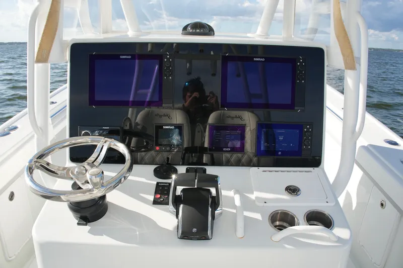 Slide: The Image of 2014 Yellowfin 32 Offshore boat dashboard with multiple Simrad displays and steering wheel. - 58