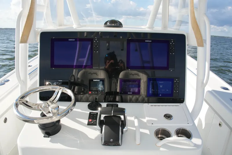 Slide: The Image of 2014 Yellowfin 32 Offshore boat dashboard with Simrad displays and steering wheel. - 36