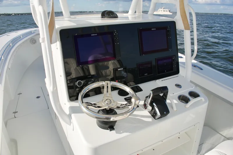 Slide: The Image of Control panel of a 2014 Yellowfin 32 Offshore boat with navigation screens and steering wheel. - 38