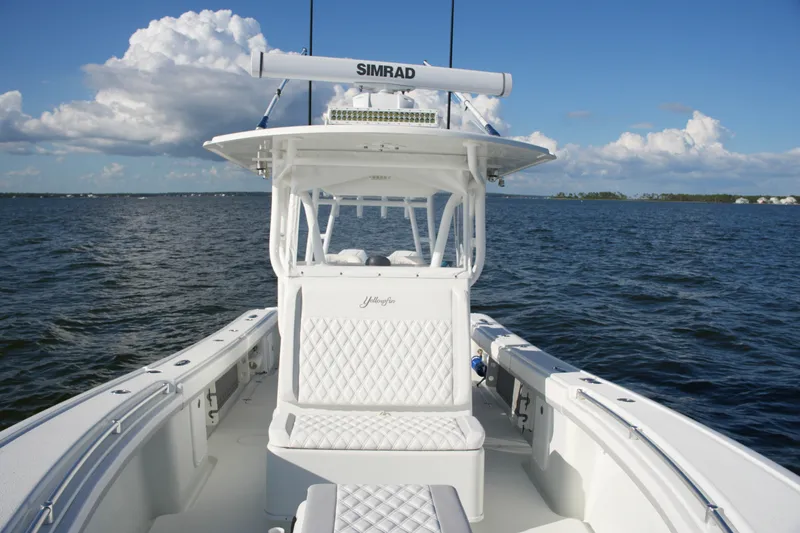 Slide: The Image of 2014 Yellowfin 32 Offshore boat on open water, featuring white seating and Simrad electronics. - 50
